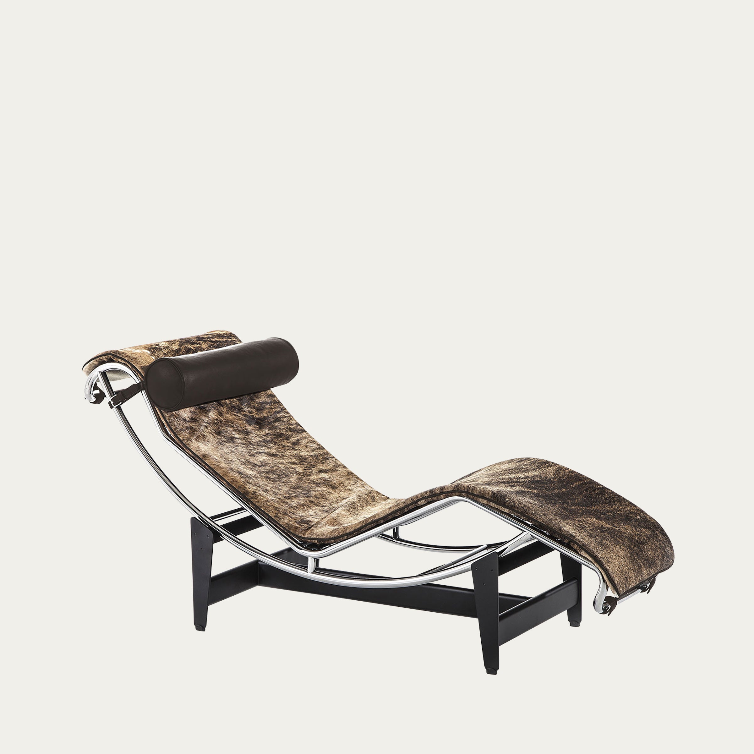 Schrägansicht der LC4 Chaise Longue von Le Corbusier mit braun gemustertem Kuhfell und schwarzer Kopfrolle